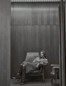 Model seated in a leather armchair against a wood paneled wall for Vogue Portugal