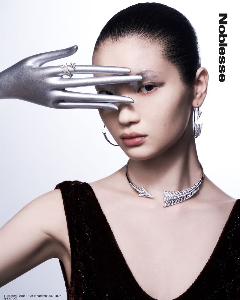 Asian woman wearing a low-cut velvet dress, silver choker, silver earrings, ring and silver metallic painted arm and hand.