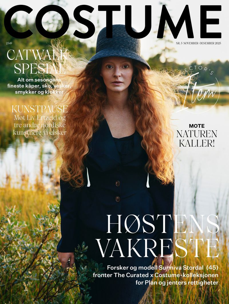 Magazine cover featuring a fair-skinned woman with long red hair, wearing a dark hat and jacket, in front of a blurred nature scene.