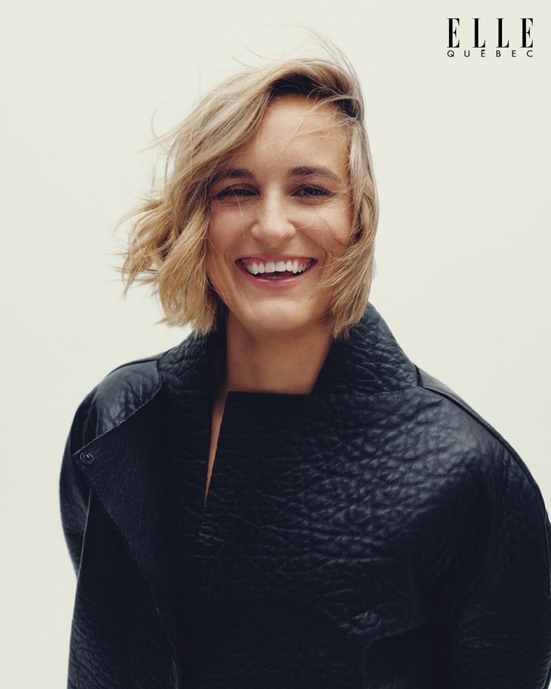 Portrait of Marie-Philip Poulin smiling in a black textured coat against a plain white background for Elle Quebec