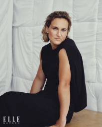 Portrait of Marie-Philip Poulin wearing a sleeveless black dress against a white quilted background for Elle Quebec.