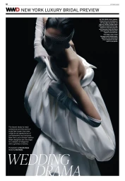Model in voluminous white bridal gown wearing a netted face veil and white gloves against a dark background.
