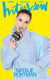 Natalie Portman in a blue striped pajama top holding a metallic teapot against a solid yellow background for Interview Magazine.