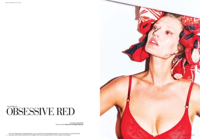 A fair-skinned woman with red headscarf and red lingerie poses against a stark white background with cool lighting in a fashion editorial.