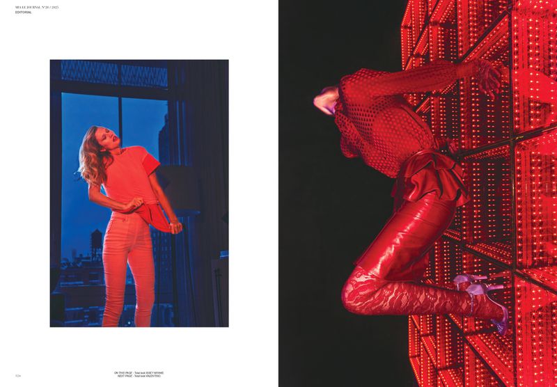 Fashion editorial featuring a female model in a red outfit next to a window with a city view and a model in a red suit and heels.