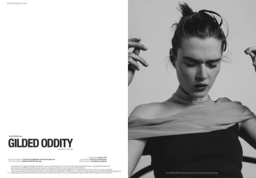Black and white portrait of a woman wearing an off-shoulder top and a crystal choker necklace against a neutral studio backdrop