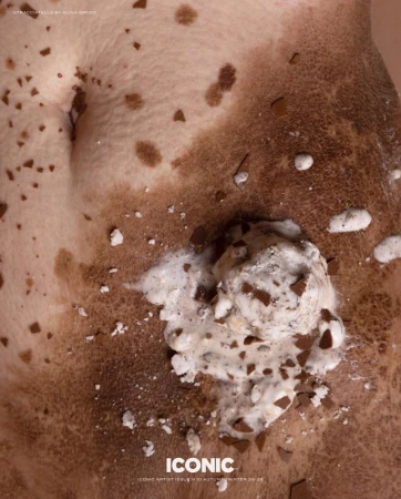 Close-up of a person's torso with uneven skin tone, freckles and an ice cream with chocolate pieces.