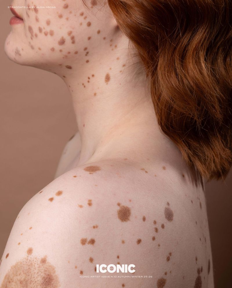 Close-up studio shot of a fair-skinned adult female with numerous freckles, short red hair, and a minimalist, natural beauty aesthetic.