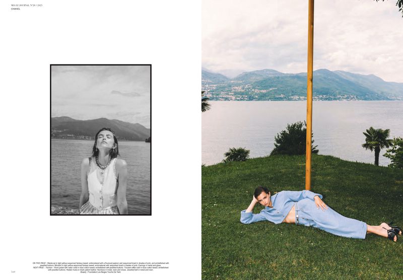 Fashion editorial layout with a model in a blue suit laying on the grass with a lake and mountains in the background, and a portrait insert.