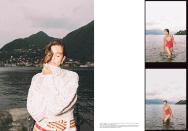 Model wearing a white knitted sweater with striped skirt by a dark lake with mountain backdrop in a magazine layout