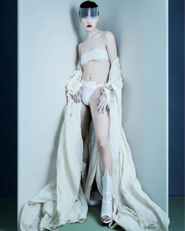 A fashion shot features a slender woman in a white bra and underwear, with a matching robe and cowboy boots, leaning against a corner.