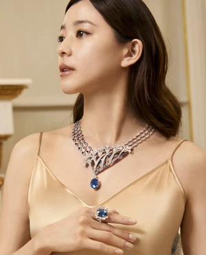 Aya Asahina wearing an ornate Chaumet sapphire and diamond necklace with a matching ring and champagne slip dress.