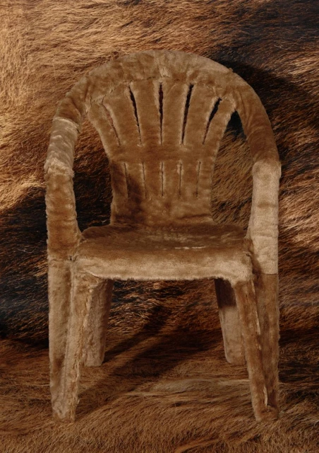 Fur-covered armchair on a brown fur rug, studio lighting. The chair and rug share a similar brown tone and a long-hair fur texture.