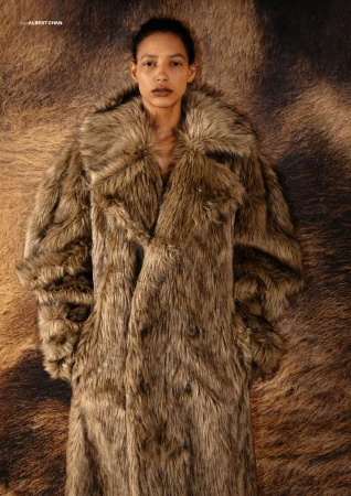 Model MJ Herrera wearing an oversized brown shaggy faux fur coat against a matching textured fur backdrop.