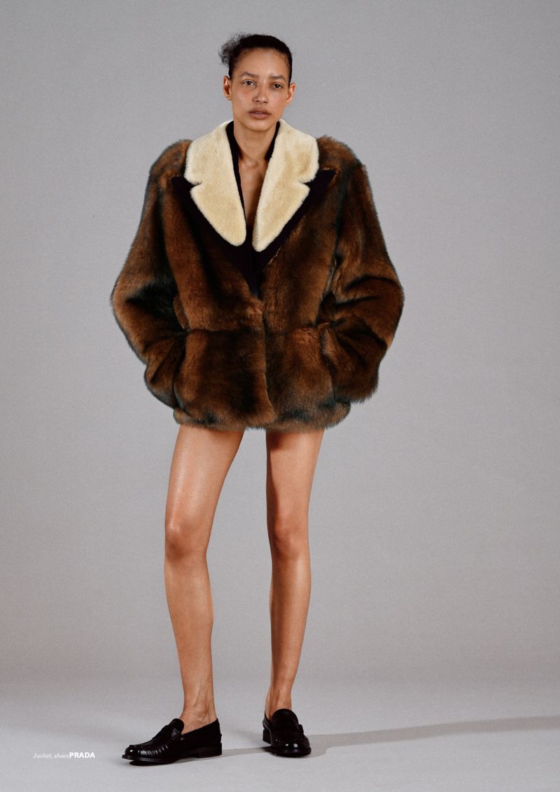 A fashion shot features a female model in a fur coat with a light-colored collar and black loafers, set against a grey background.