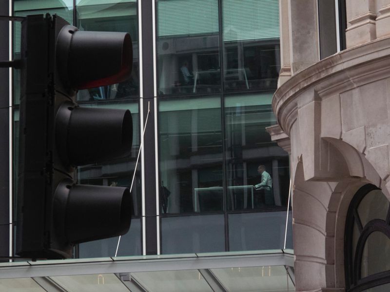 Urban scene featuring a black traffic light in the foreground with modern office building behind and traditional stone building.