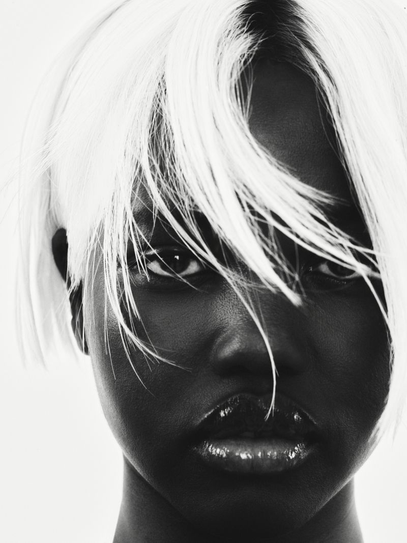 Close-up portrait of a woman with short white hair and dark skin against a white background in a beauty fashion style.