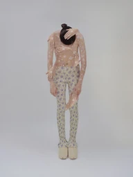 Model wearing a sheer patterned top and floral leggings surrounded by multiple superimposed hands against a plain white background