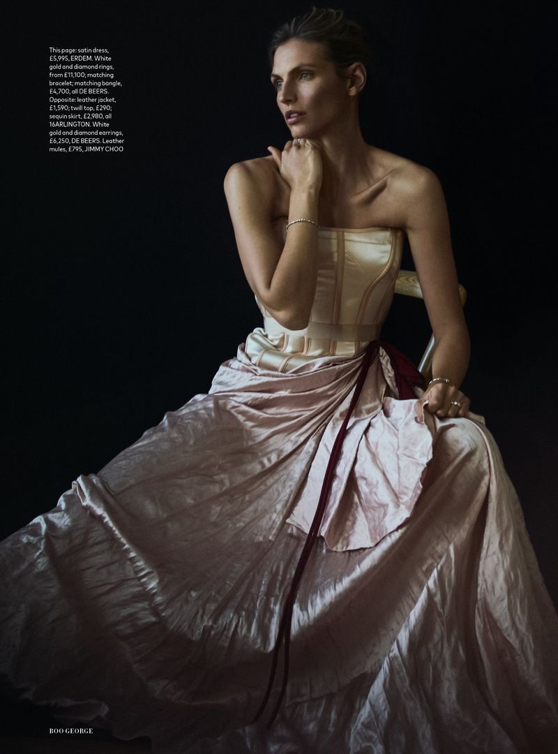 Model Karlina Caune wearing a structured strapless dress seated against a dark background for Harper's Bazaar UK.