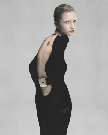 Model in black backless dress with metallic cuff against a plain grey backdrop for Wallpaper China