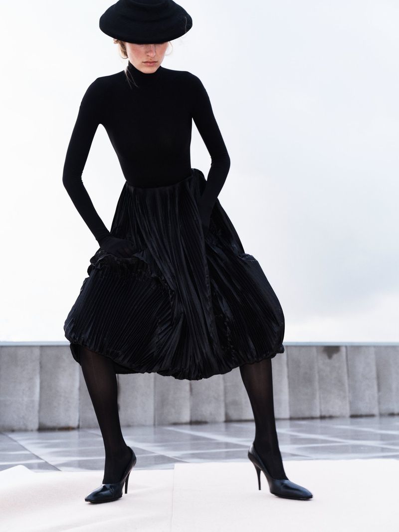 Model Felice Nova Noordhoff in black turtleneck, pleated skirt, and wide-brim hat for SSAW Magazine story