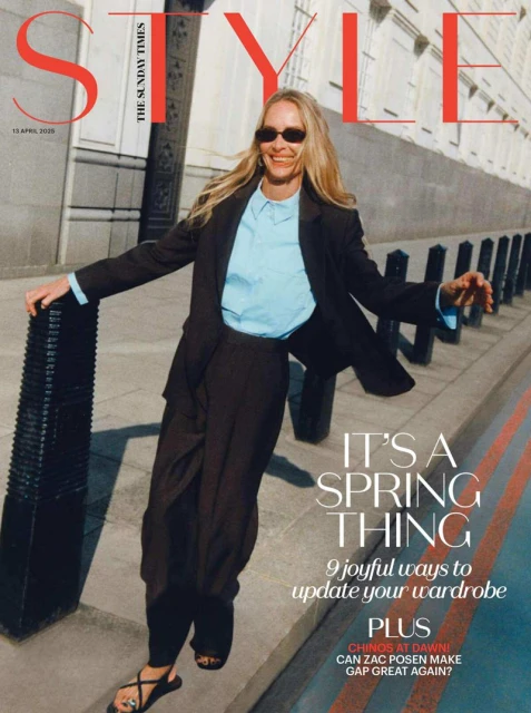 Model Georgina Grenville wearing a black suit and blue shirt outdoors on a city street for The Sunday Times Style Magazine