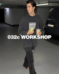 Bruno Sharif walking in an underground parking garage wearing a black 032c sweatshirt and holding two green drinks.