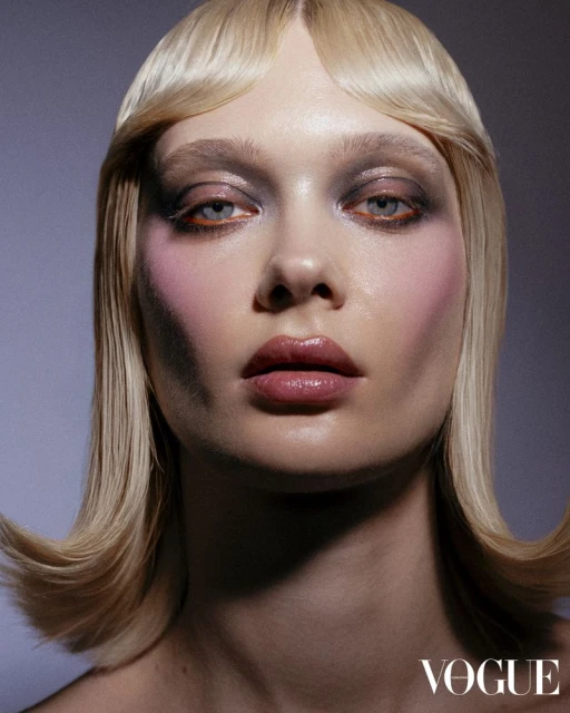 Close-up portrait of a blonde adult female with creative make-up, light skin, glossy lips, posing in a studio. Beauty, fashion.