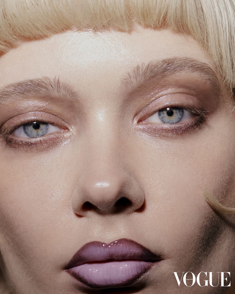 Close-up beauty portrait of a model with blue eyes, blonde hair, and dark lip liner for Vogue Hong Kong.