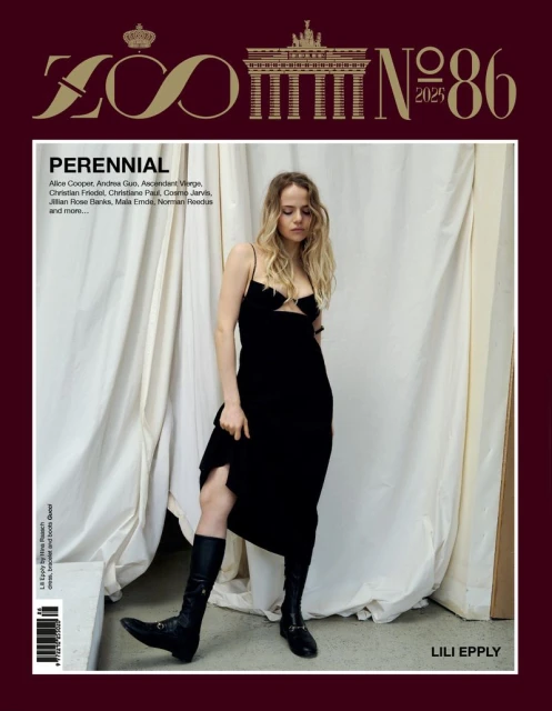 Magazine cover featuring a blonde woman in a black dress and boots standing before draped fabric