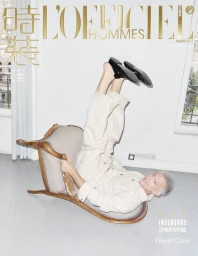 Actor Vincent Cassel lying upside down on a chaise lounge in a white room for an editorial cover.