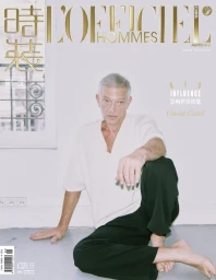 Vincent Cassel seated on a studio floor wearing a white short-sleeve shirt and dark trousers for L'Officiel Hommes China April 2025