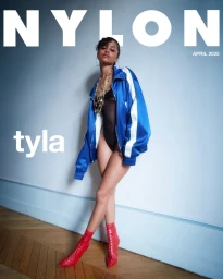 Tyla posing for Nylon Magazine April 2025 cover wearing a blue track jacket, black bodysuit, and red boots.