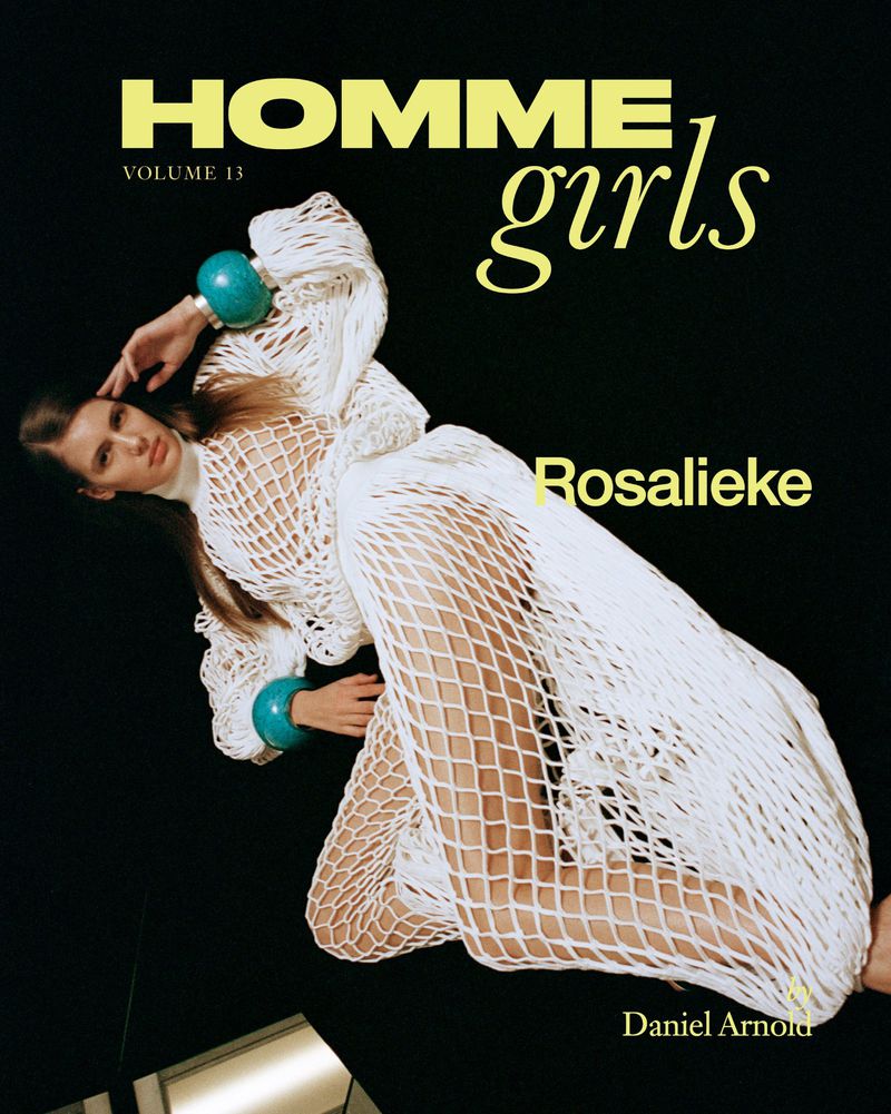 Fashion magazine cover with a model posing in a white net dress against a black background, featuring bold yellow text.