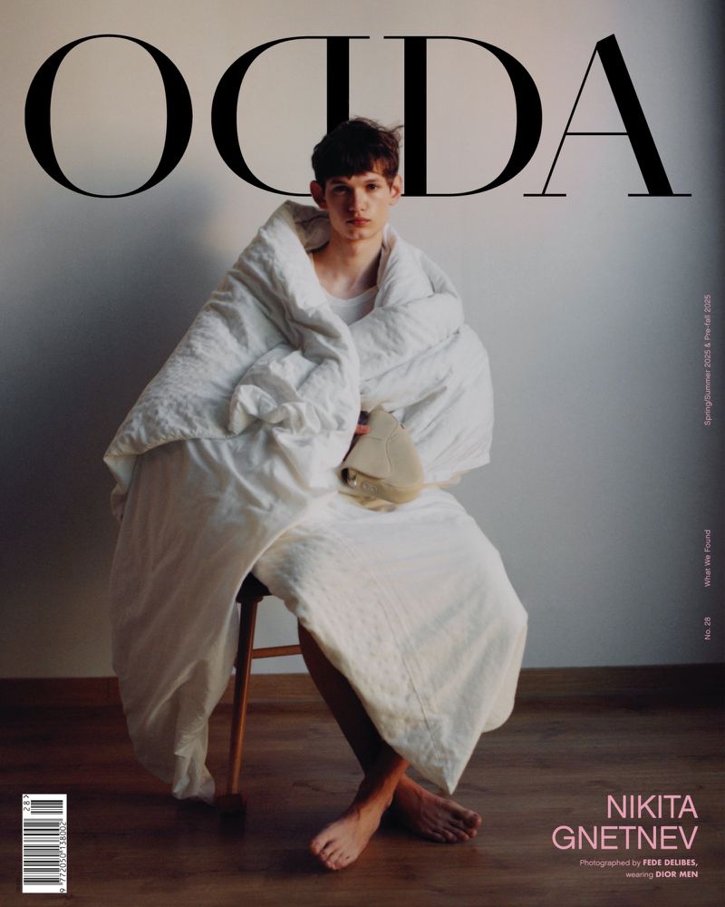 Magazine cover featuring a young man seated on a wooden stool, wrapped in a white blanket with large text 'OCDA' at the top.