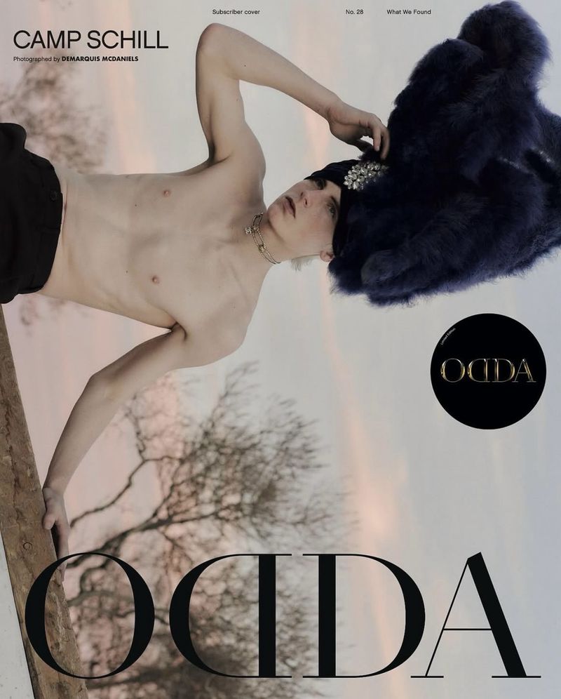 Magazine cover featuring a shirtless young man with a jeweled hat, black bottoms, and a necklace, set against a blurred outdoor background.