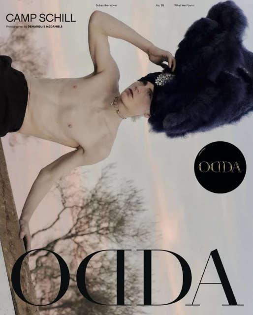 Magazine cover featuring a shirtless young man with a jeweled hat, black bottoms, and a necklace, set against a blurred outdoor background.
