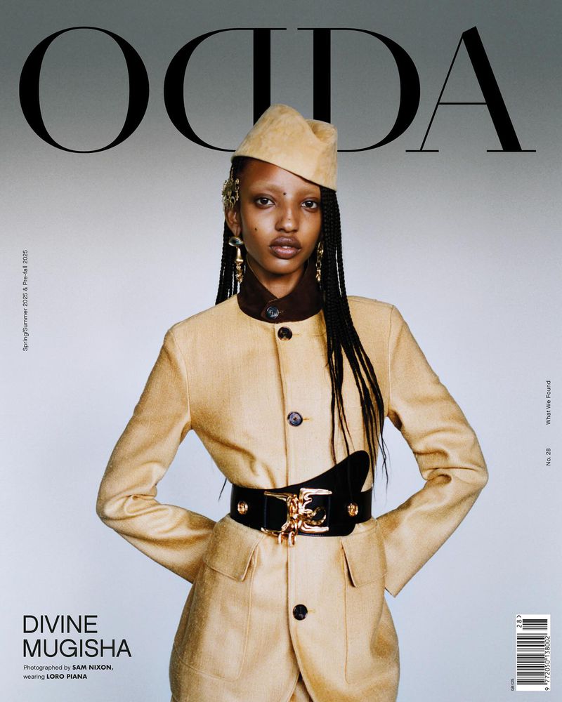 Magazine cover featuring model Divine Mugisha wearing a tan jacket, matching cap, black belt, and gold earrings against a grey background.
