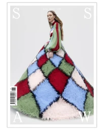 Model standing inside a large voluminous patchworked skirt against a plain white studio background