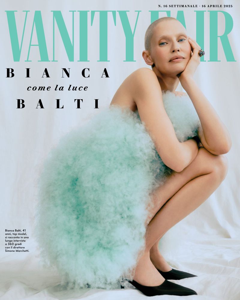 Bianca Balti cover image for Vanity Fair, featuring a bald adult female model in a light blue dress crouching indoors.