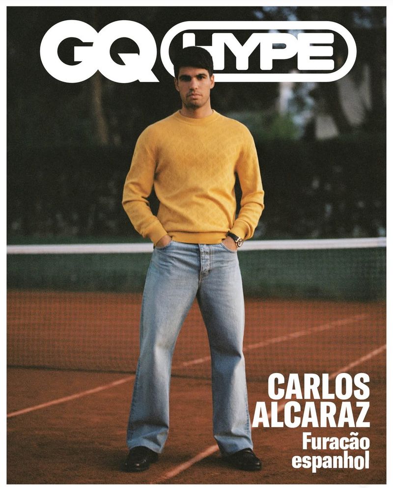 Magazine cover featuring a man in a yellow sweater and jeans standing on a tennis court with a net in the background.