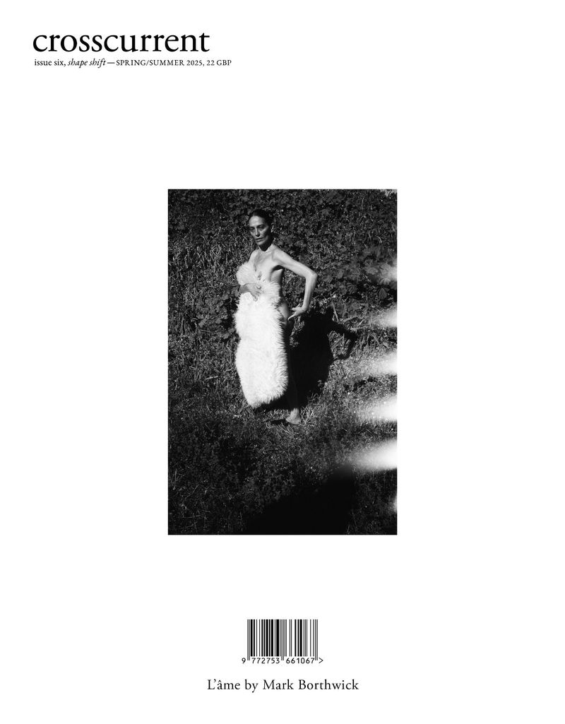 Black and white magazine cover featuring a woman in a fur coat against a grassy background, with the 'crosscurrent' logo at the top.