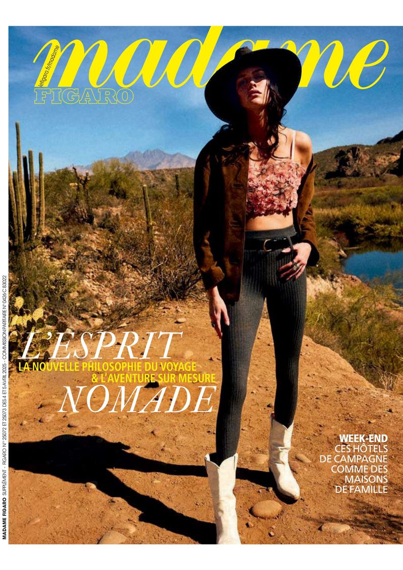 Magazine cover featuring a model in a brown jacket, floral top, and cowboy boots standing in a desert landscape with cacti and mountains.