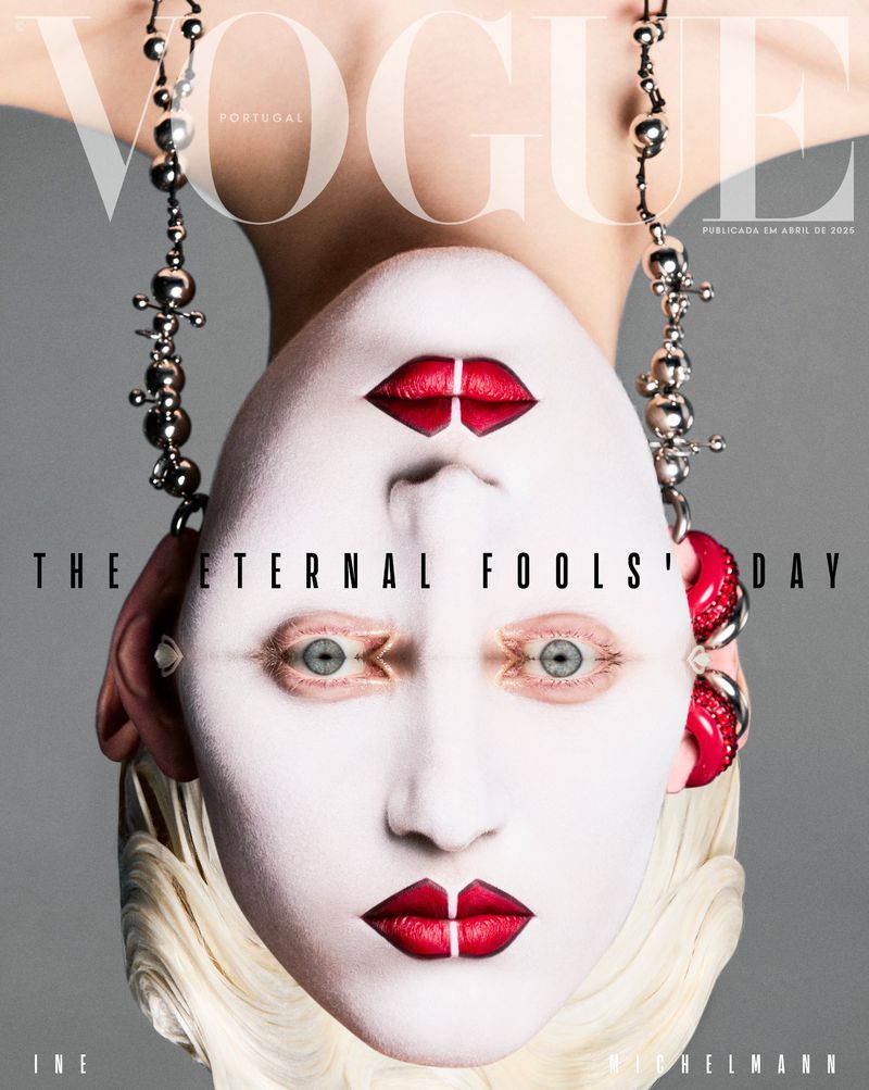 Conceptual fashion cover features a person with stylized white makeup, red lips, and bold jewelry against a gray background.