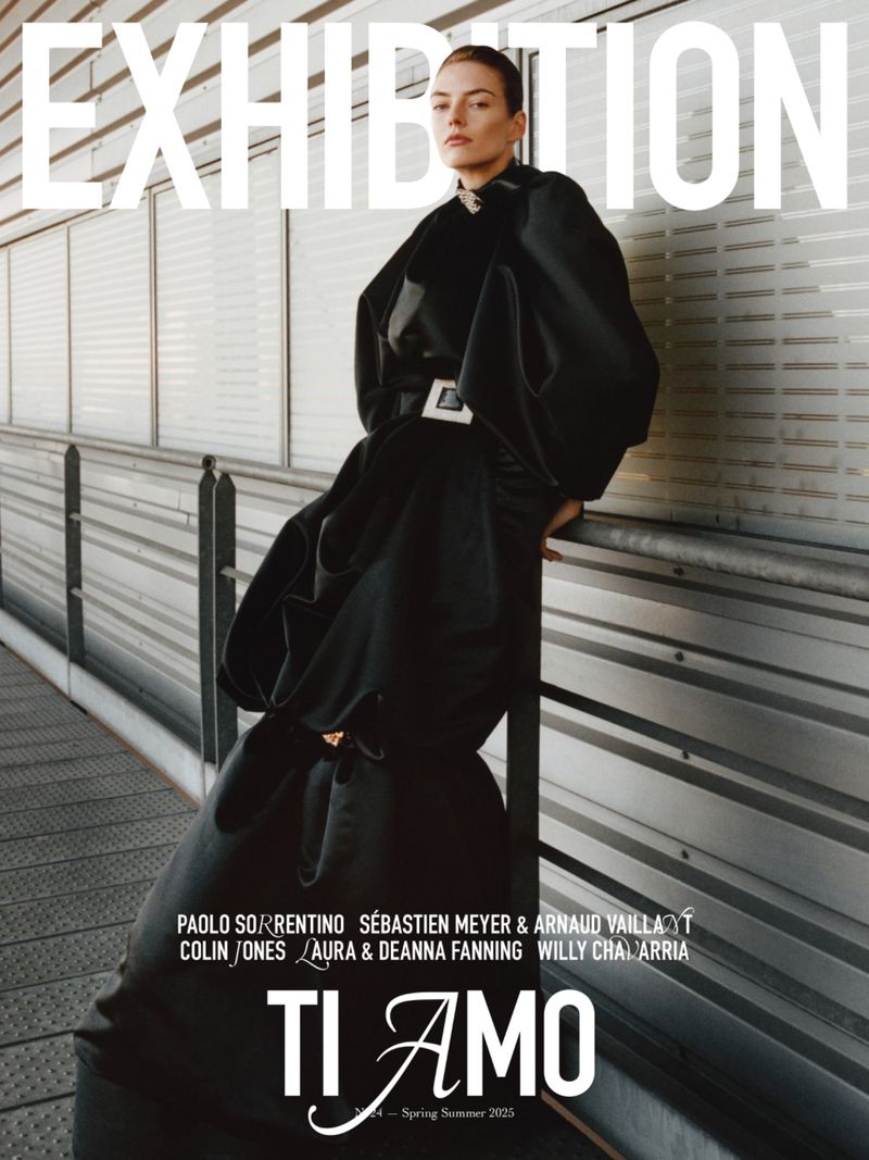 Fashion magazine cover featuring an adult female model in a long black dress, posing against a neutral-toned architectural background.