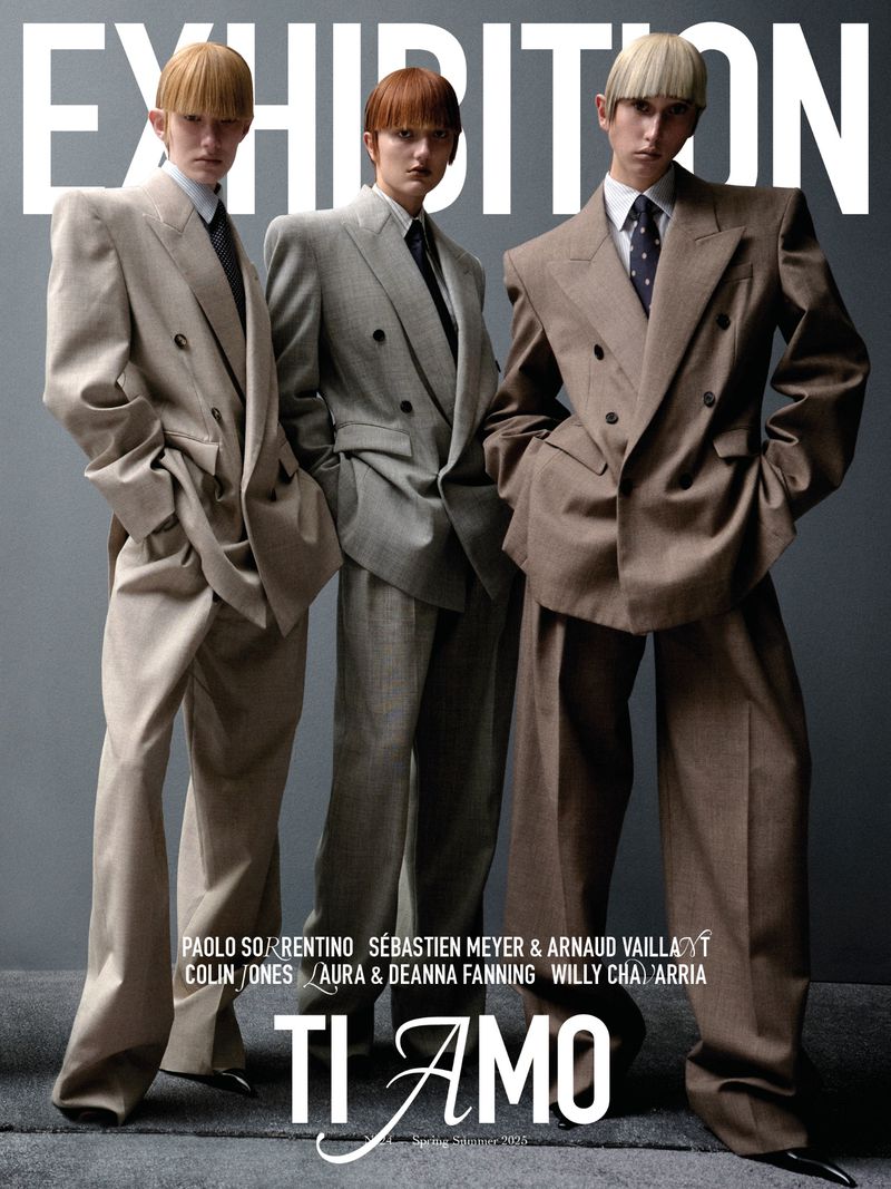 Three models wearing oversized tailored suits and blunt bangs against a grey studio backdrop for Exhibition Magazine