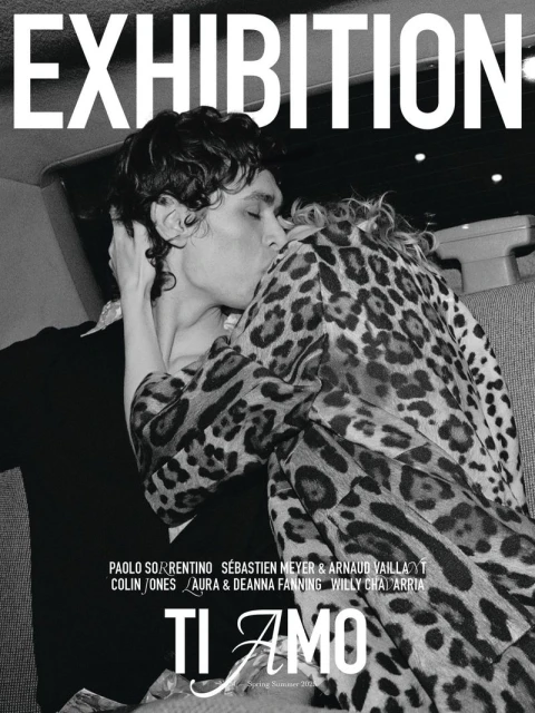 Editorial image of a couple embracing; the man is kissing the woman's cheek. The woman wears a leopard print jacket. 'Exhibition' text at the top.