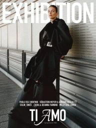 Model in black sculptural coat leaning against a metallic railing for Exhibition Magazine