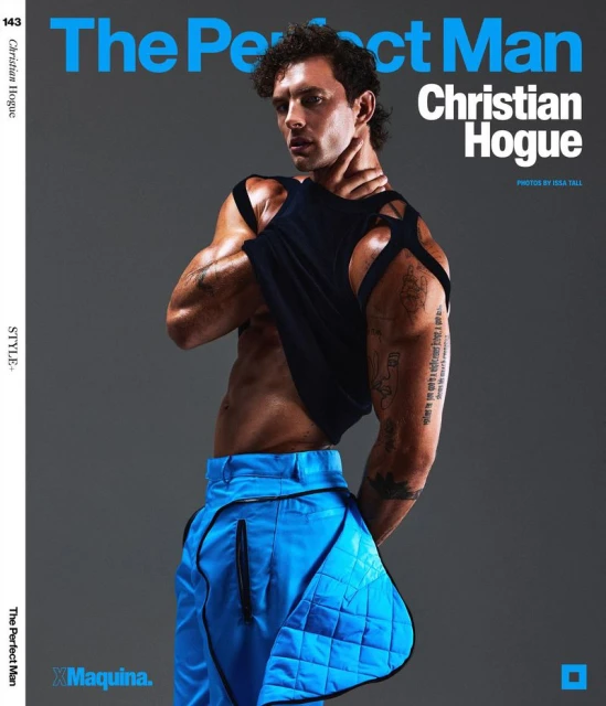 Magazine cover featuring a shirtless male fashion model with muscular build wearing blue pants in a studio shot with grey background.