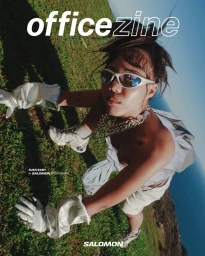 Model wearing silver futuristic sunglasses and metallic gloves on a grassy coastal hillside for Office Magazine